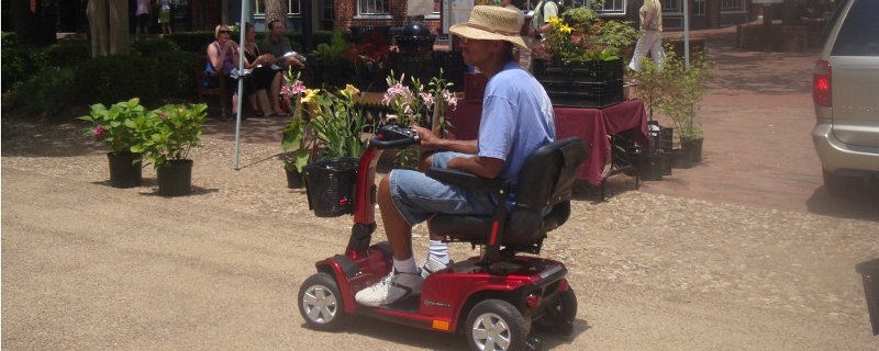 A man wearing a hat riding an electrical scooter