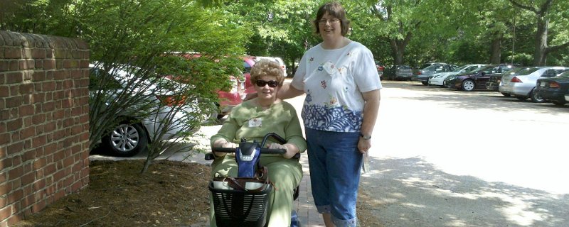 A woman smiling and riding an electric scooter